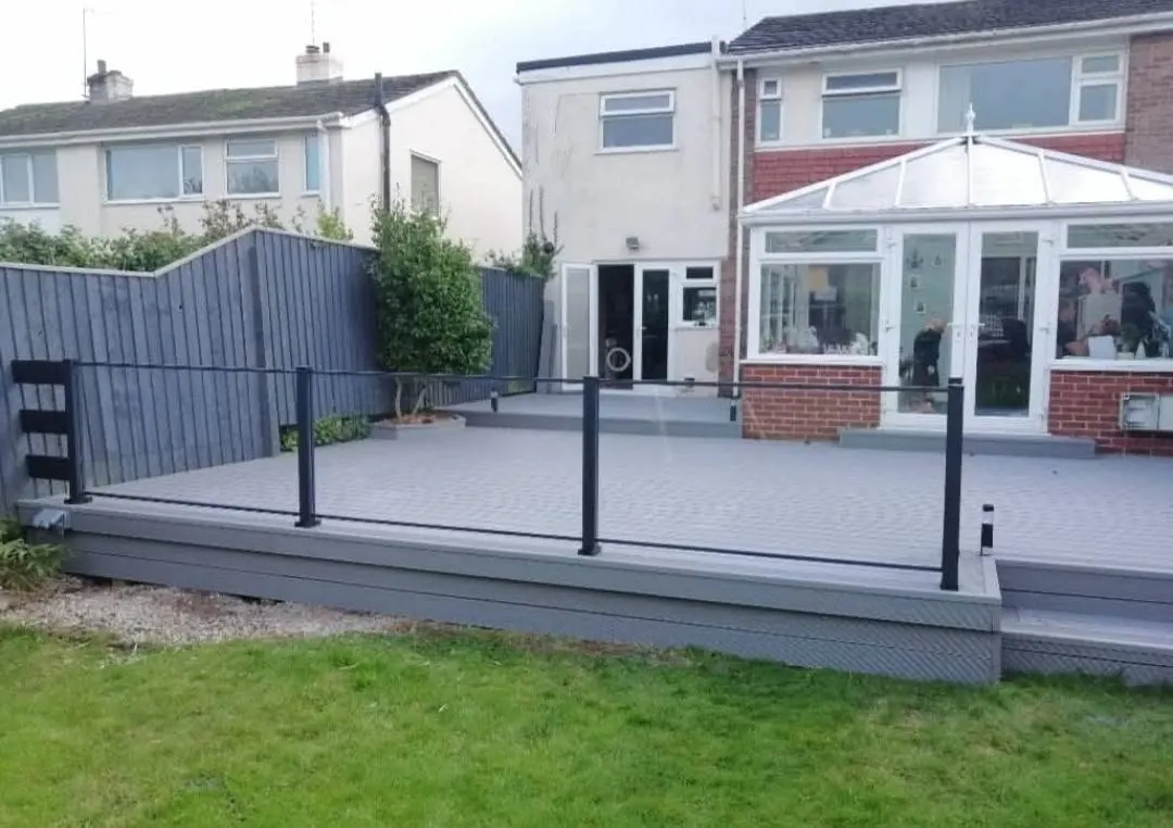 Composite deck with glass balustrade beside a conservatory