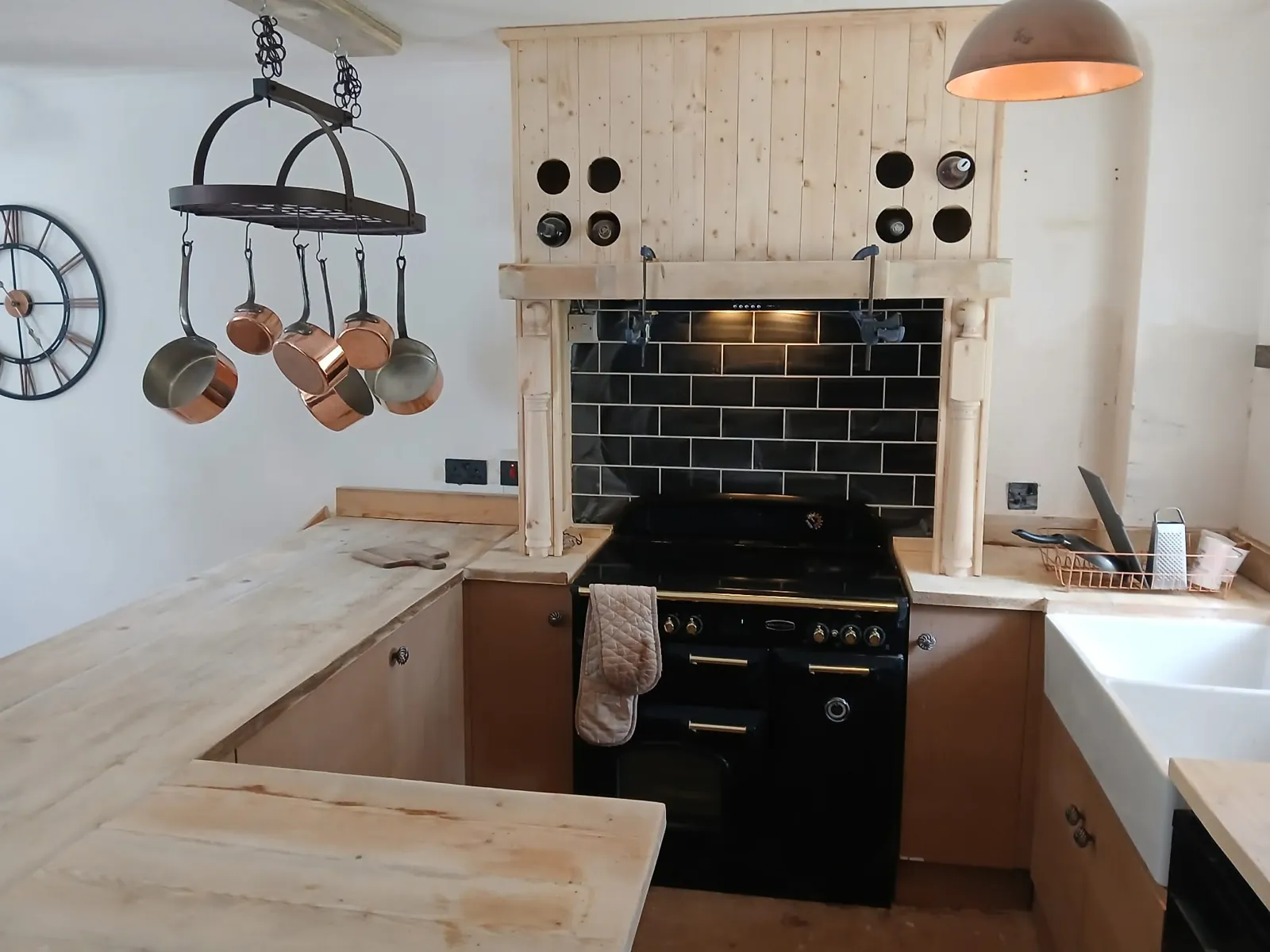 Bespoke timber cooker surround, mantel and worktops in a country kitchen with black range cooker