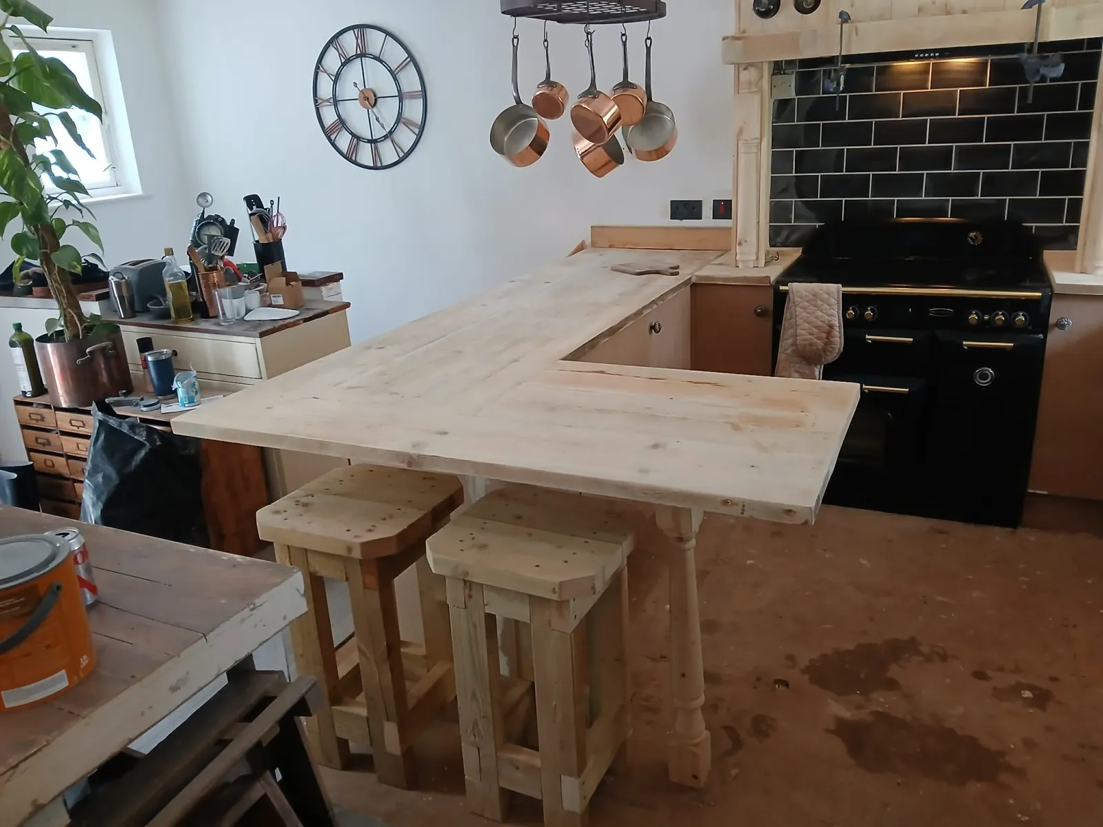 Handmade timber breakfast bar and stools in a fitted kitchen with black range cooker